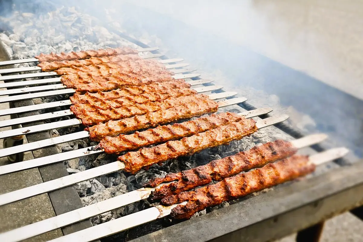 Adana kebab grilling over charcoal